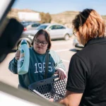Velocity support worker helping a client load groceries into a car